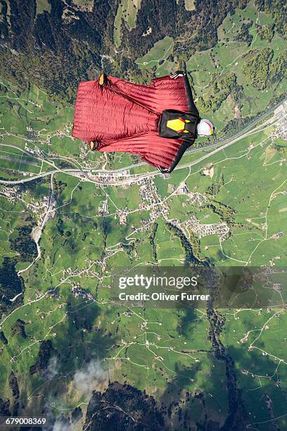 man in a wingsuit is soaring high in the clear sky - skydiving pov stock pictures, royalty-free photos & images