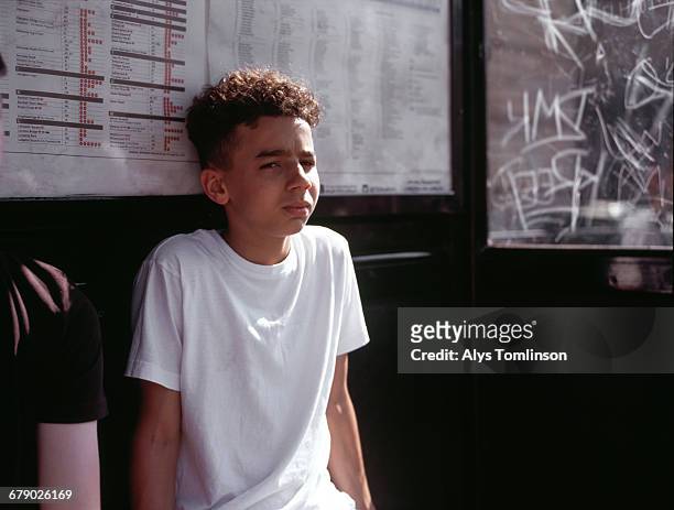 Young, teenage boy waiting at London bus stop