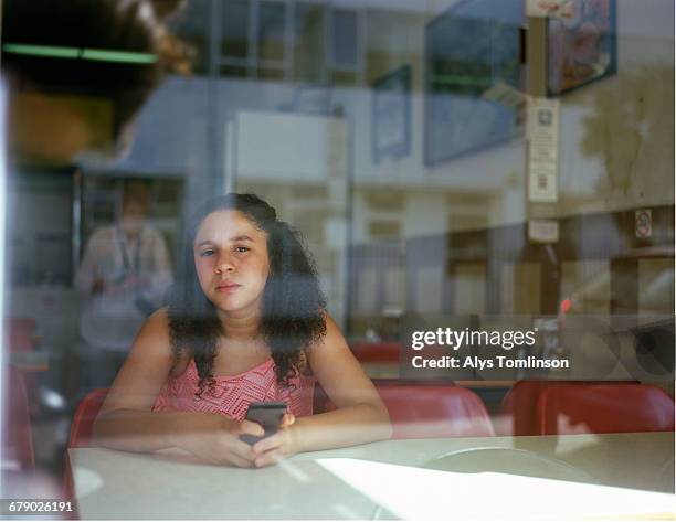 Portrait of teenage girl through window of a cafe