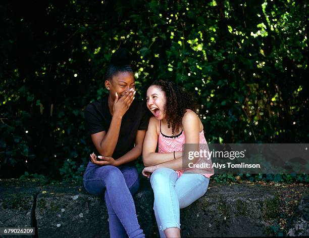 Two teenage girls laughing together in a park