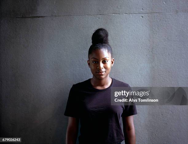portrait of teenage girl standing against wall - alleen één tienermeisje stockfoto's en -beelden
