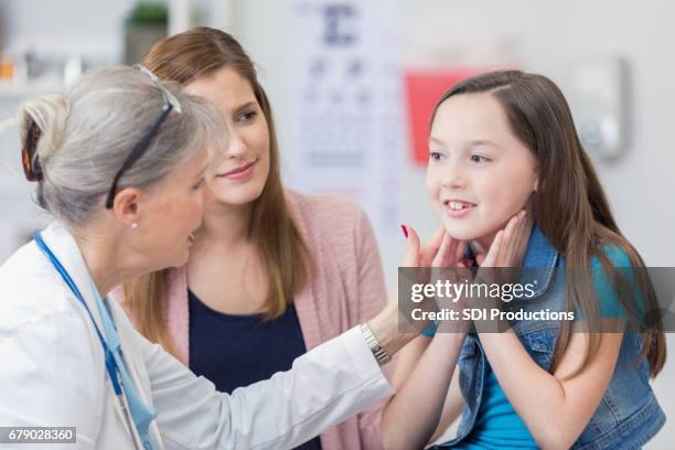 vertrouwen senior vrouwelijke kinderarts onderzoekt jong meisje - allergy doctor stockfoto's en -beelden