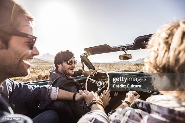 over shoulder view of three men on the road driving convertible, franschhoek, south africa - toyota south africa motors stock pictures, royalty-free photos & images