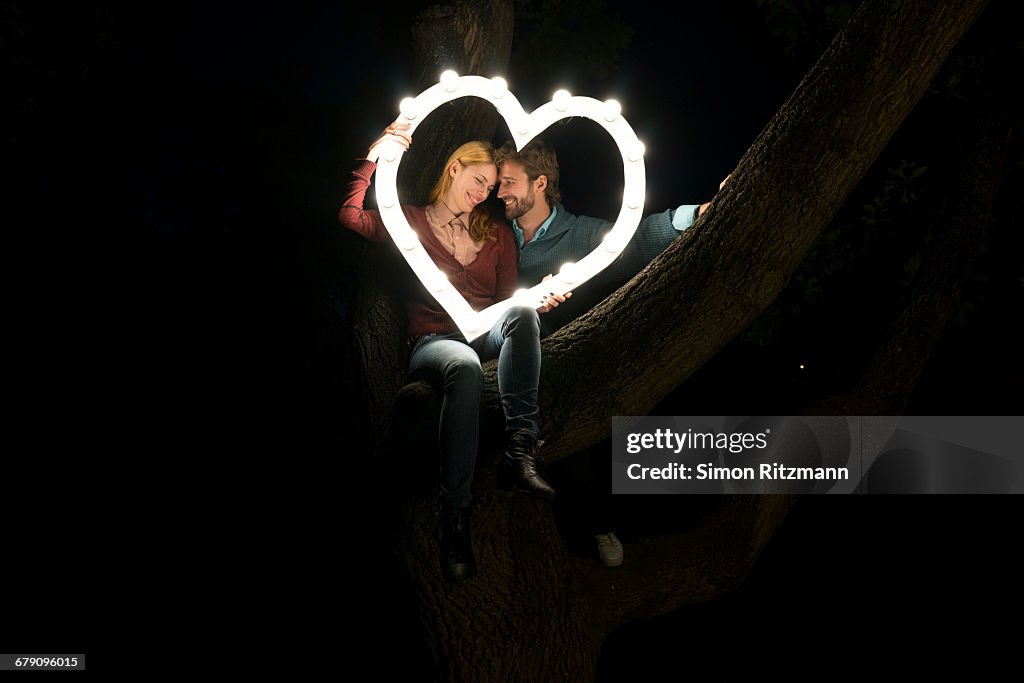 Couple in love with illuminated heart on tree