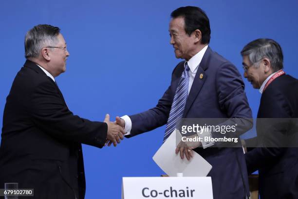 Carlos Dominguez, the Philippines' secretary of finance, left, and Taro Aso, Japan's deputy prime minister and finance minister, shake hands after a...