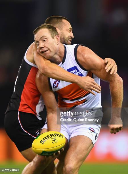 Steve Johnson of the Giants handballs whilst being tackled Jarryn Geary of the Saints during the round seven AFL match between the St Kilda Saints...