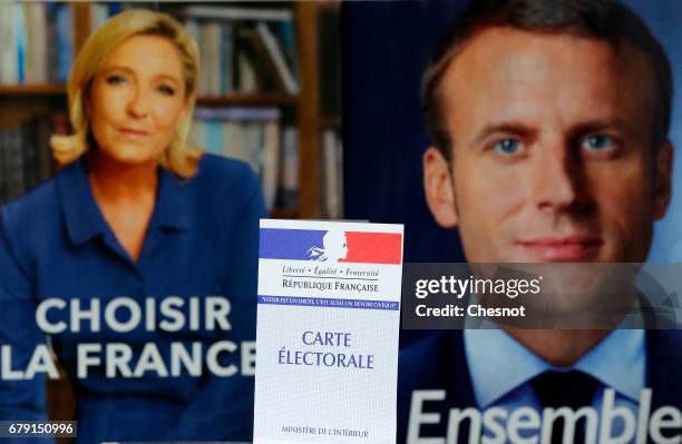 In this photo illustration, a French voter registration card is seen in front of official campaign posters of candidates in the French presidential...