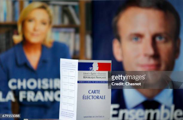 In this photo illustration, a French voter registration card is seen in front of official campaign posters of candidates in the French presidential...