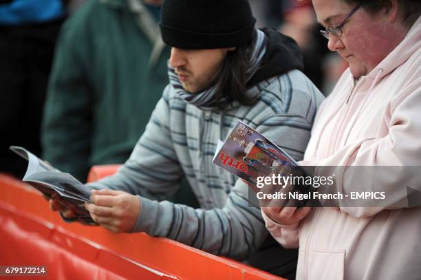 Fans read the match day programme in the stands before the game