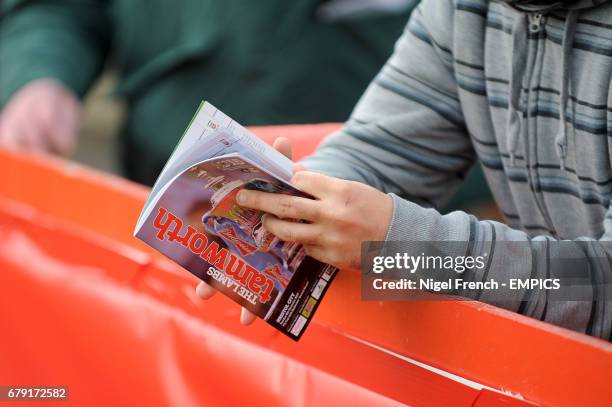Fans read the match day programme in the stands before the game