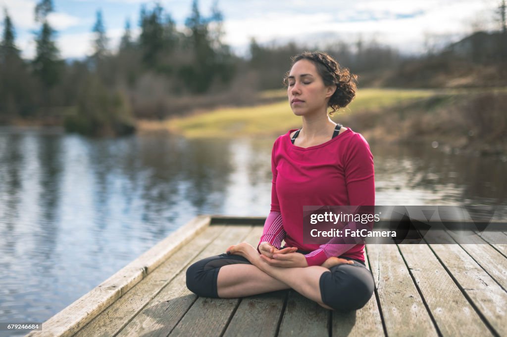 Young mom doing yoga outside by lake