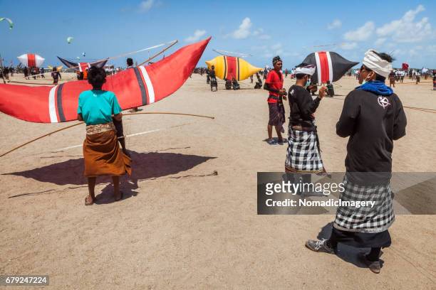 kite flyers with kites wait on bali beach for competition to commence - indonesian kite stock pictures, royalty-free photos & images
