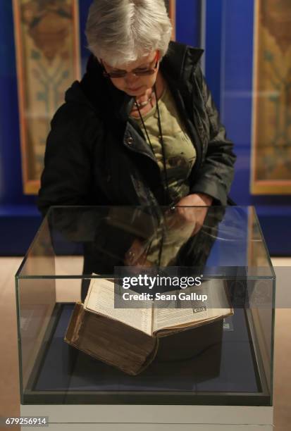 Visitor, who said she did not mind being photographed, looks at an edition of Martin Luther's 95 theses printed in Basel in 1517, the same year that...