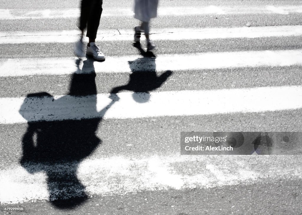 Blurry shadow of mother and child crossing the street