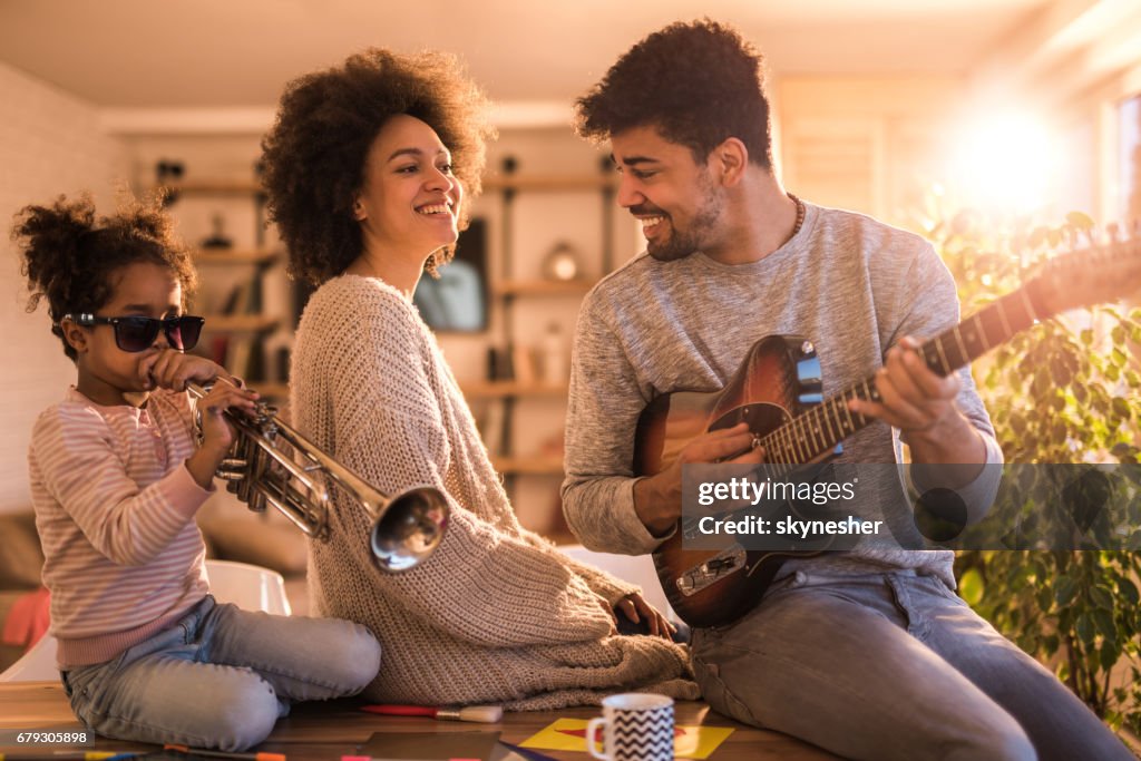 Playful black family having fun while playing musical instruments at home.