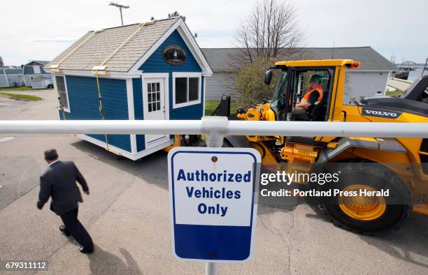 Chuck Gregory, academic dean of Southern Maine Community College, left, walks past a shed being moved by Howie Hall, driver of the front-end loader....