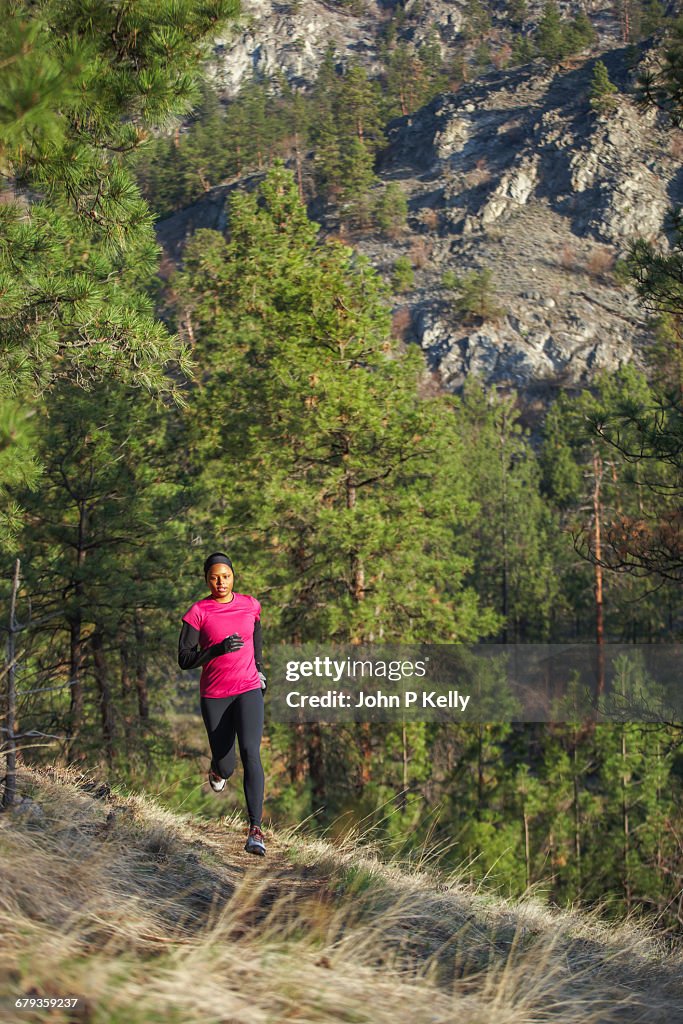 Young woman jogs along mountain trail