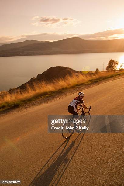 cyclists rides on scenic beach road at sunset - racing bicycle stock pictures, royalty-free photos & images