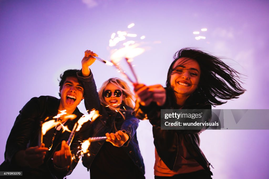 Group of young friends having fun with fireworks outdoors