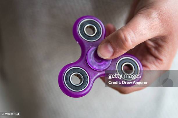 In this photo illustration, a woman holds a fidget spinner, May 5, 2017 in the Brooklyn borough of New York City. Fidget spinners have become the...