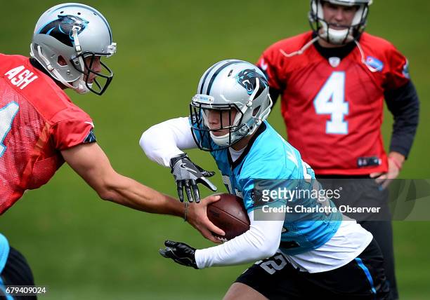 Carolina Panthers rookie running back Christian McCaffrey takes a handoff from quarterback David Ash, left, during the second session of the team's...