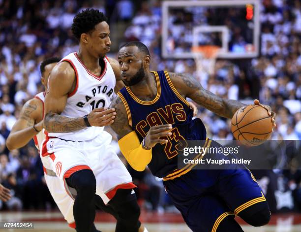 Lebron James of the Cleveland Cavaliers dribbles the ball as DeMar DeRozan of the Toronto Raptors defends in the second half of Game Three of the...