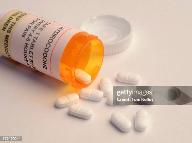 Close-up of an opened prescription bottle, labelled as containing the opioid hydrocodone, as a number of its pills lie on a white surface, March 14,...