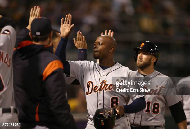 Justin Upton and Tyler Collins of the Detroit Tigers are congratulated by teammates after they scored on a hit by Jim Adduci in the sixth inning...