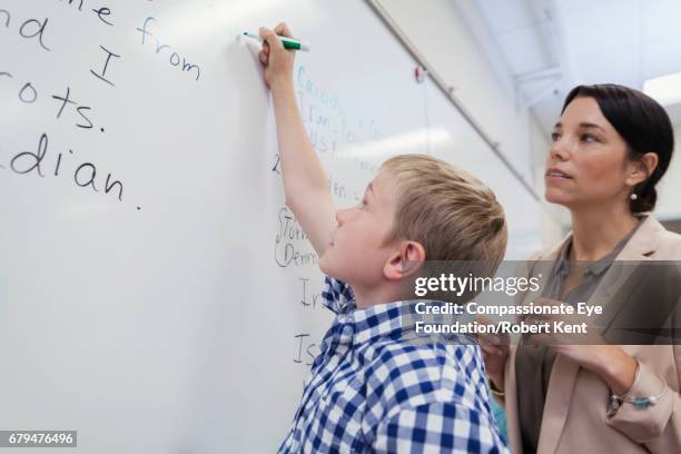 teacher and student at white board in classroom - english language stock pictures, royalty-free photos & images