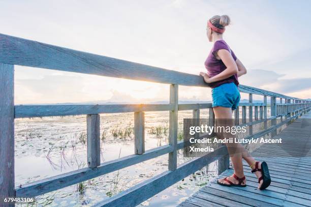 young woman looks off from marsh boardwalk - short sleeved stock pictures, royalty-free photos & images