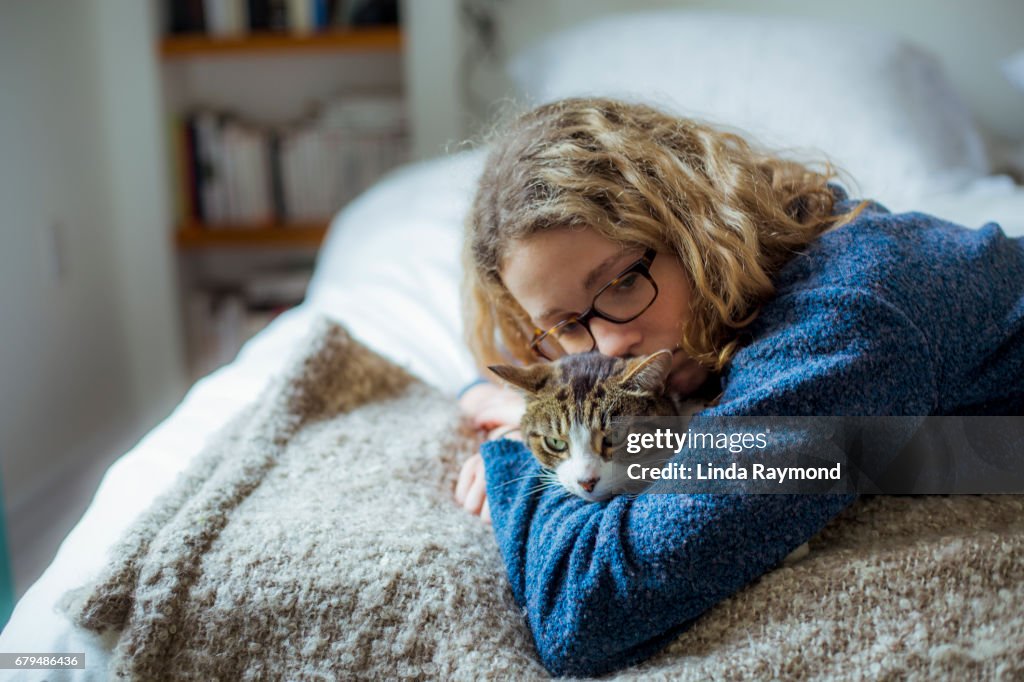 Home Moments - A girl hugging her tabby cat on a bed