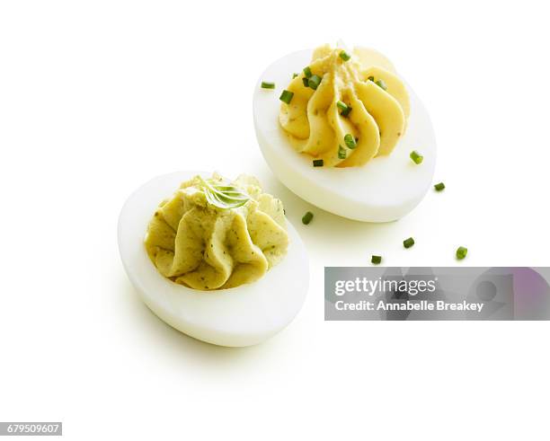 two deviled eggs garnished on white - deviled egg stock pictures, royalty-free photos & images