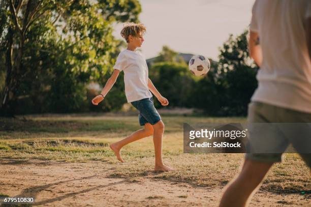 young boy playing soccer in the park - teen boy barefoot stock pictures, royalty-free photos & images