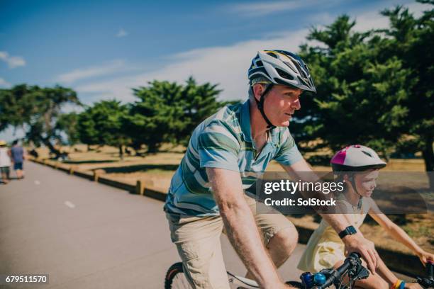 father and daughter cycling in the park - melbourne australia stock pictures, royalty-free photos & images