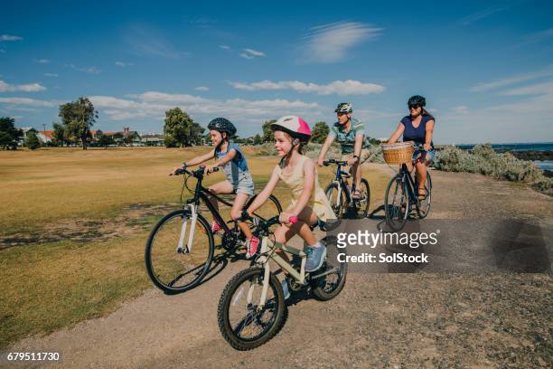 family of four cycling in the park - two kids with cycle imagens e fotografias de stock