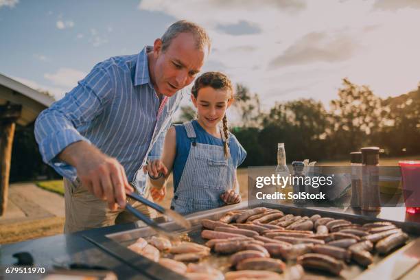 helping dad cook sausages on the bbq - summer grilling stock pictures, royalty-free photos & images