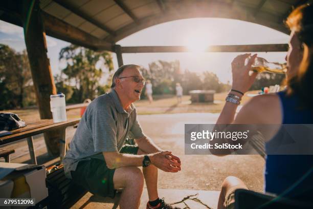 senior man sitting at a picnic bench in the park - candid moments stock pictures, royalty-free photos & images