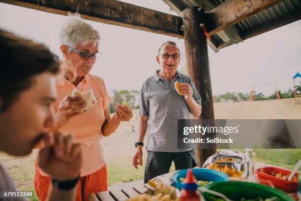 senior paar genieten van voedsel op een bbq - australian bbq stockfoto's en -beelden