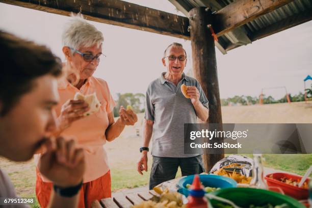 senior couple enjoying food at a bbq - bbq australia stock pictures, royalty-free photos & images