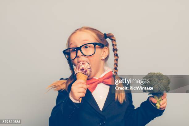 young female nerd eats ice cream and holds broccoli - broccoli stock pictures, royalty-free photos & images