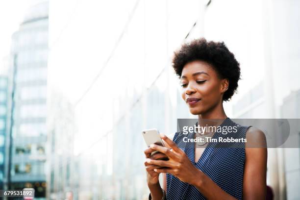 woman with mobile next to buildings - woman texting 個照片及圖片檔