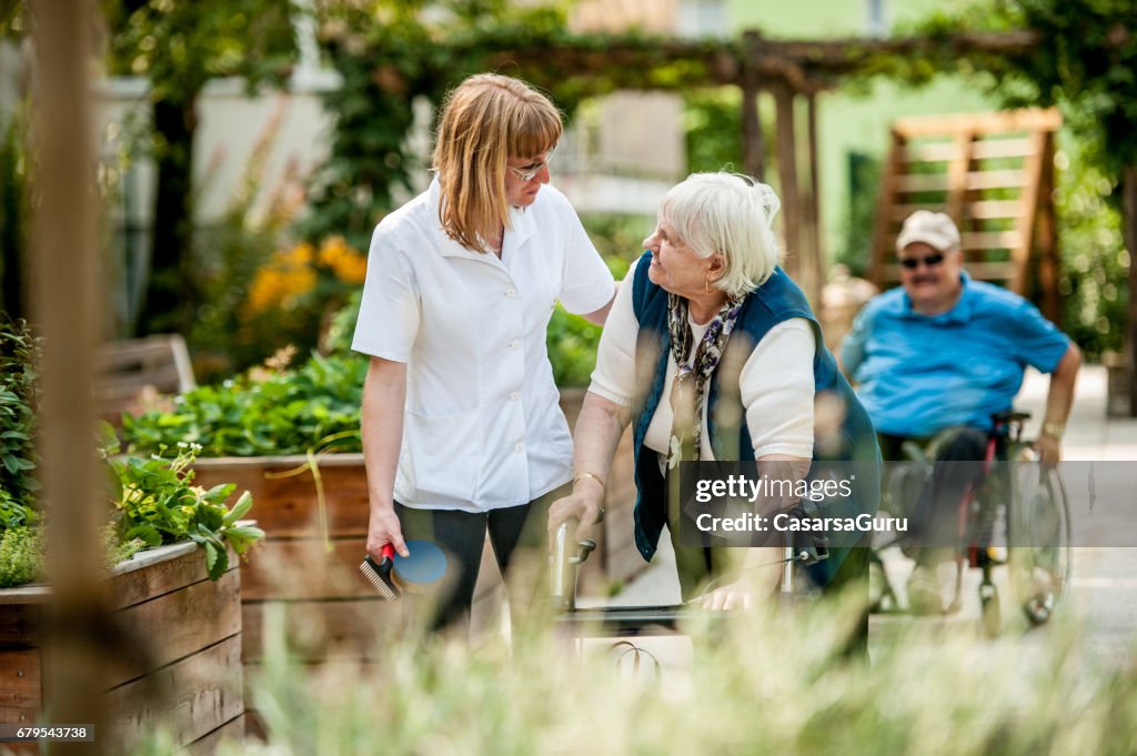 Assistant In The Retirement Community Have A Walk With The Senior Woman