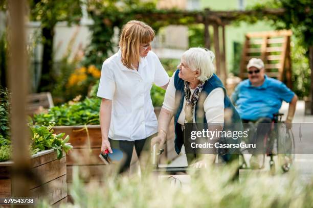 assistant in the retirement community have a walk with the senior woman - residential care stock pictures, royalty-free photos & images