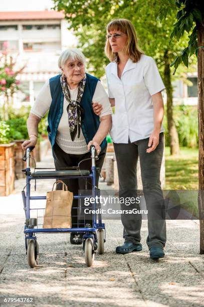 assistant in the retirement community have a walk with the senior woman - residential care stock pictures, royalty-free photos & images