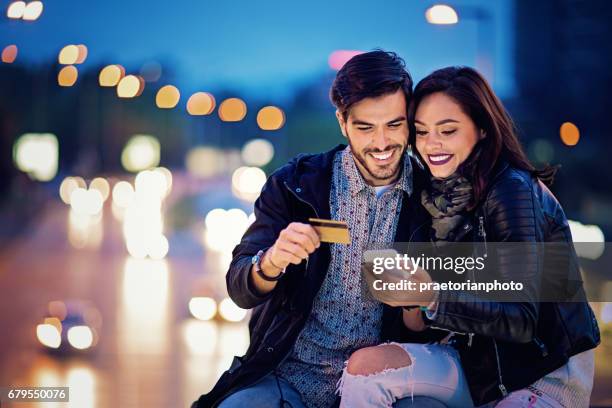 couple is shopping online on the bridge in the night - young couple shopping stock pictures, royalty-free photos & images