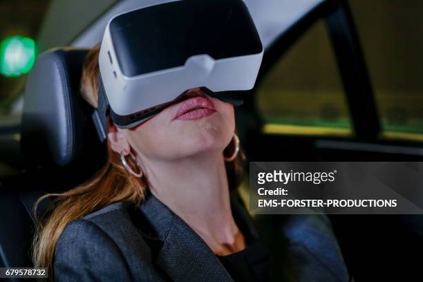 best ager woman  with vr glasses in car / taxi driving through  tunnel - best ager woman stockfoto's en -beelden