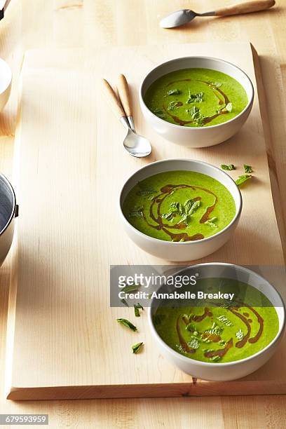 three bowls of spinach soup on wooden surface - pea and mint soup stock pictures, royalty-free photos & images
