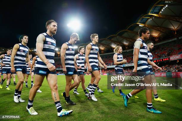 Cats players walk off dejected after defeat during the round seven AFL match between the Gold Coast Suns and the Geelong Cats at Metricon Stadium on...