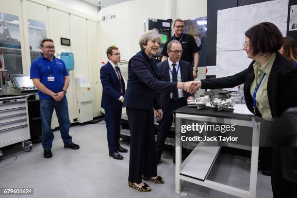 British Prime Minister Theresa May greets a worker as she tours the UTC Aerospace Systems factory with West Midlands Mayor Andy Street during a...
