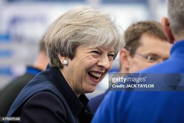 British Prime Minister Theresa May shares a laugh with a worker as she tours the UTC Aerospace Systems factory during a visit in Wolverhampton,...